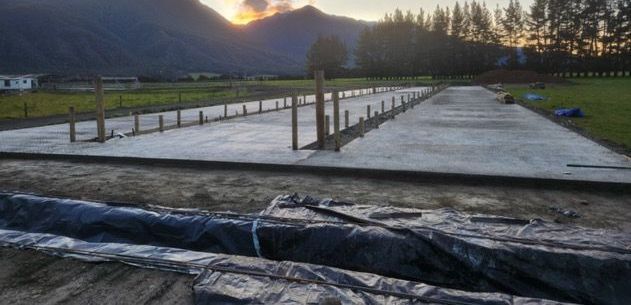 A concrete floor is being built in a field with mountains in the background.