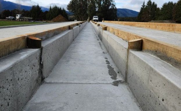 A concrete walkway with wooden beams on the side of it