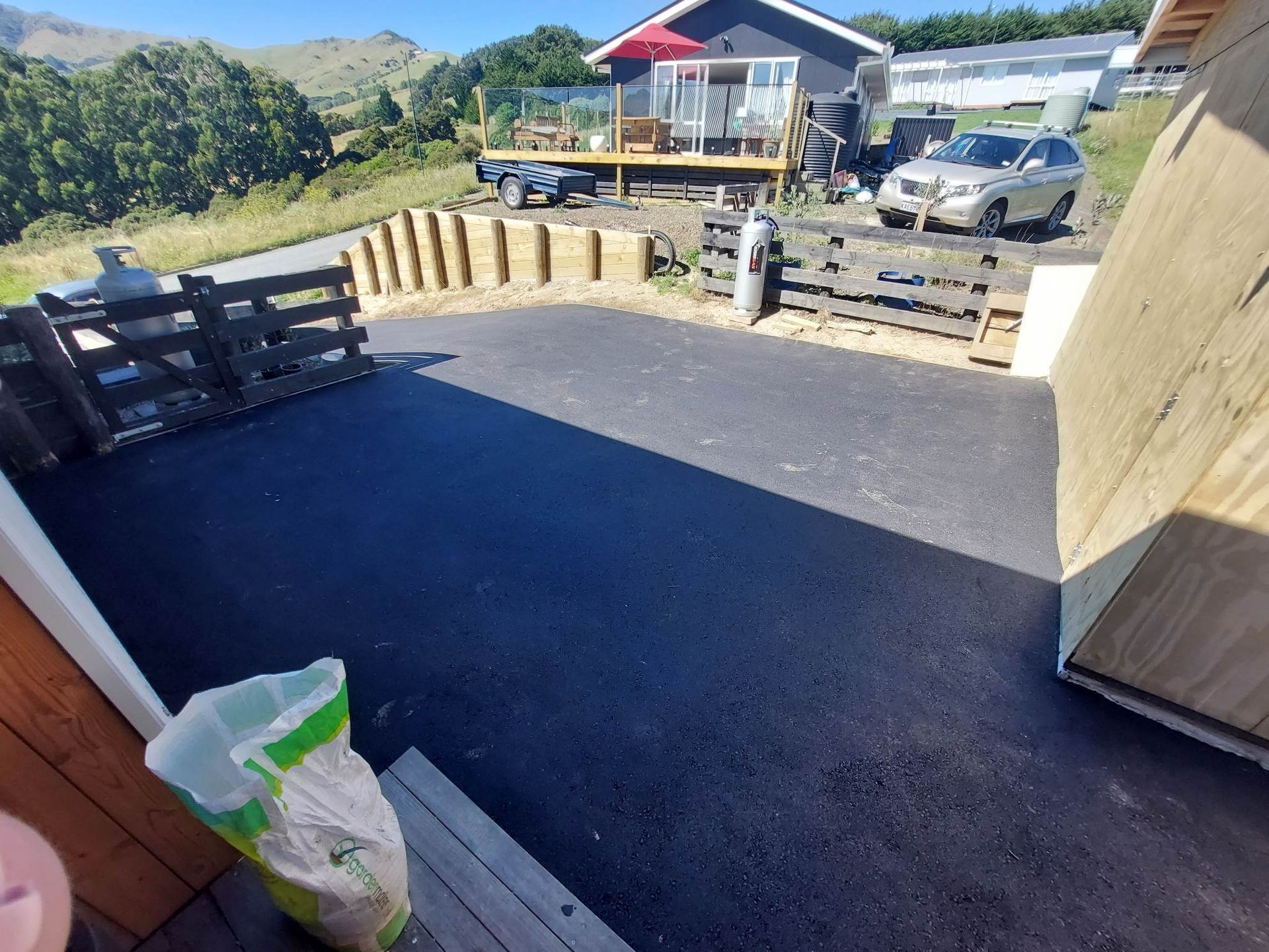 A bag of fertilizer is sitting on a porch next to a house.