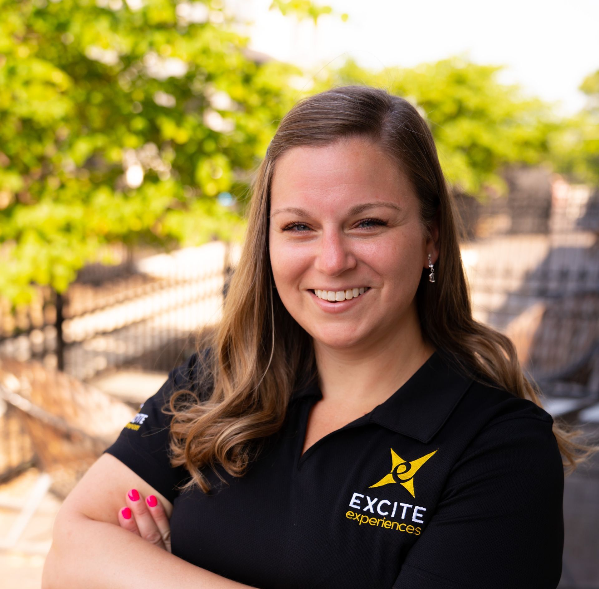 Woman with arms crossed, smiling, wearing a black shirt with 