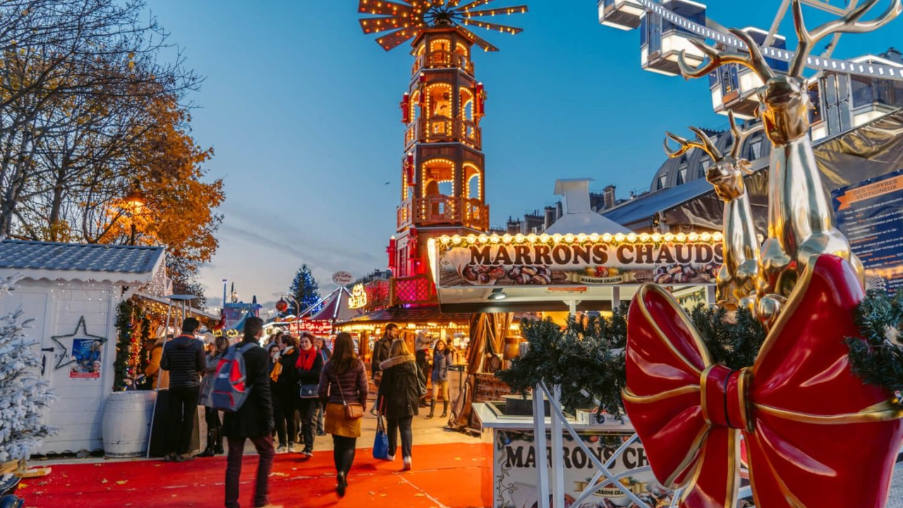 A group of people are walking down a red carpet at a christmas market.