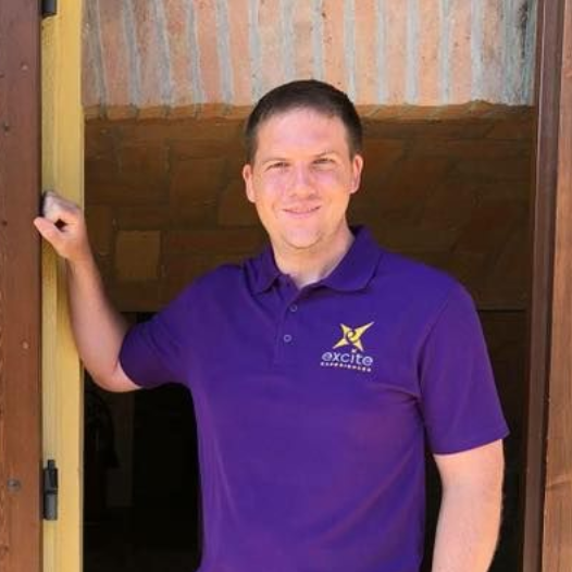Woman in purple shirt, smiling, outdoors; logo says 