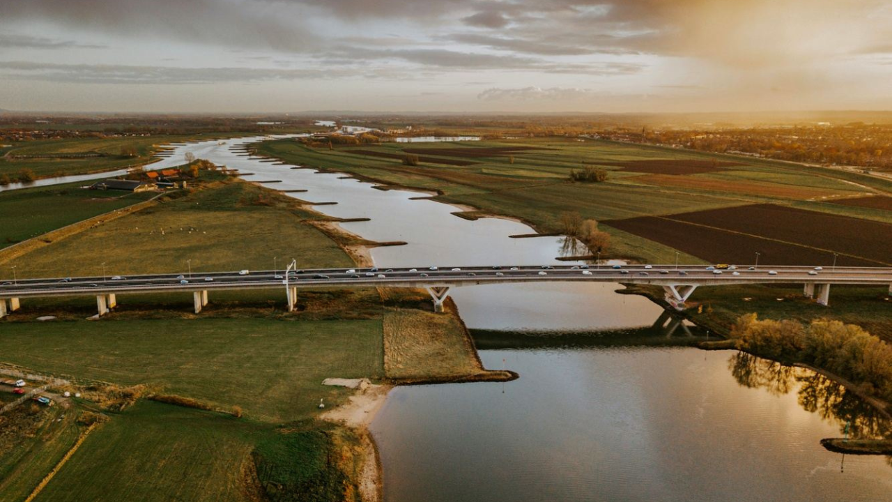 An aerial view of a bridge over a river surrounded by fields.