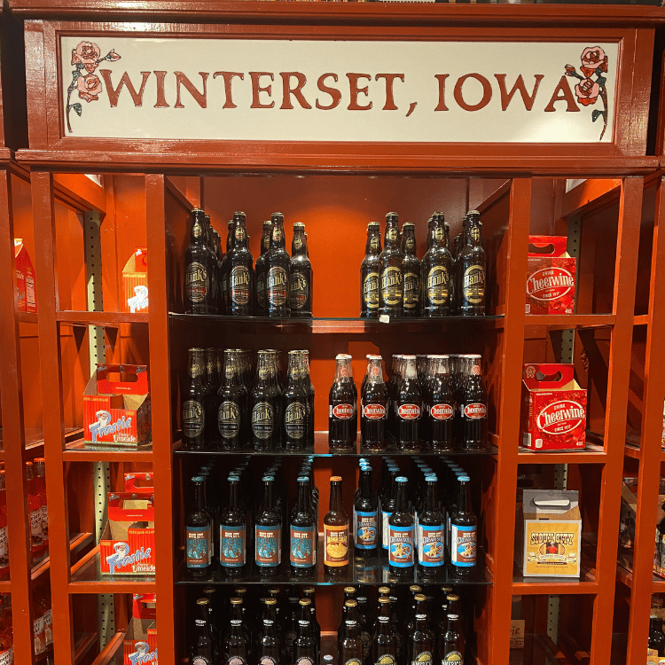 Shelf display with bottled beverages, under a sign for Winterset, Iowa.