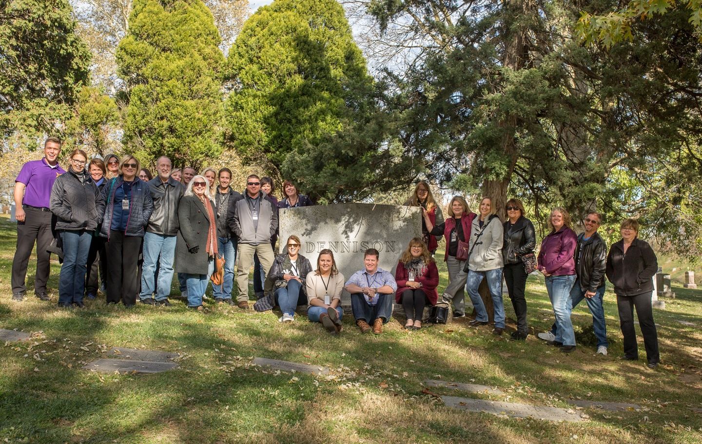 A large group of people are posing for a picture in a cemetery.