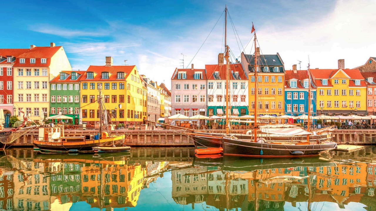 A city with boats docked in the water and buildings reflected in the water.