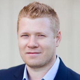 A man in a suit and white shirt is smiling for the camera.