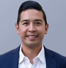 A man in a suit and white shirt is smiling for the camera.