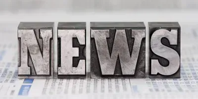 The word news is written in metal type on a newspaper.