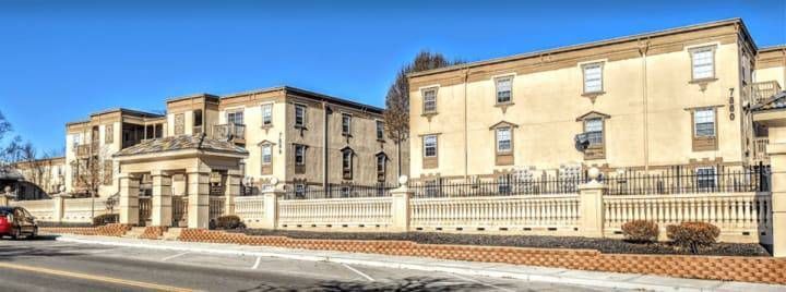 A large building with a fence around it is sitting next to a road.