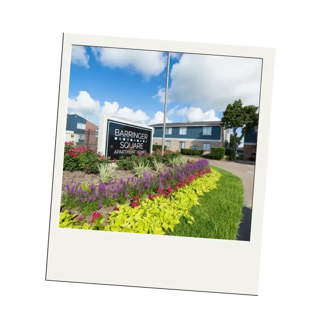 A polaroid picture of a sign in front of a building surrounded by flowers.