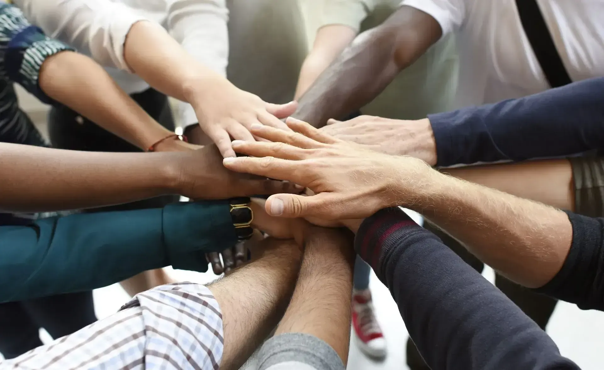 A group of people are putting their hands together in a circle.