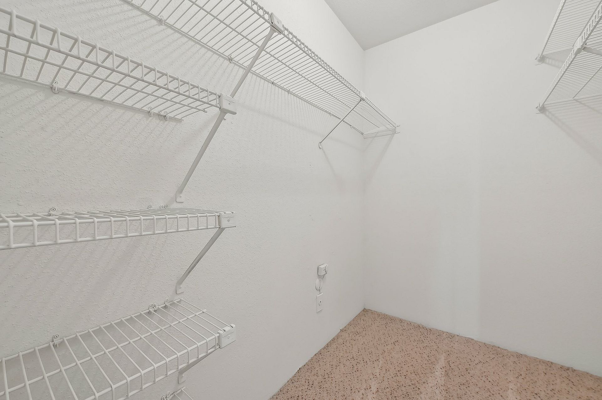 White walk-in closet with multiple wire shelves on all walls.