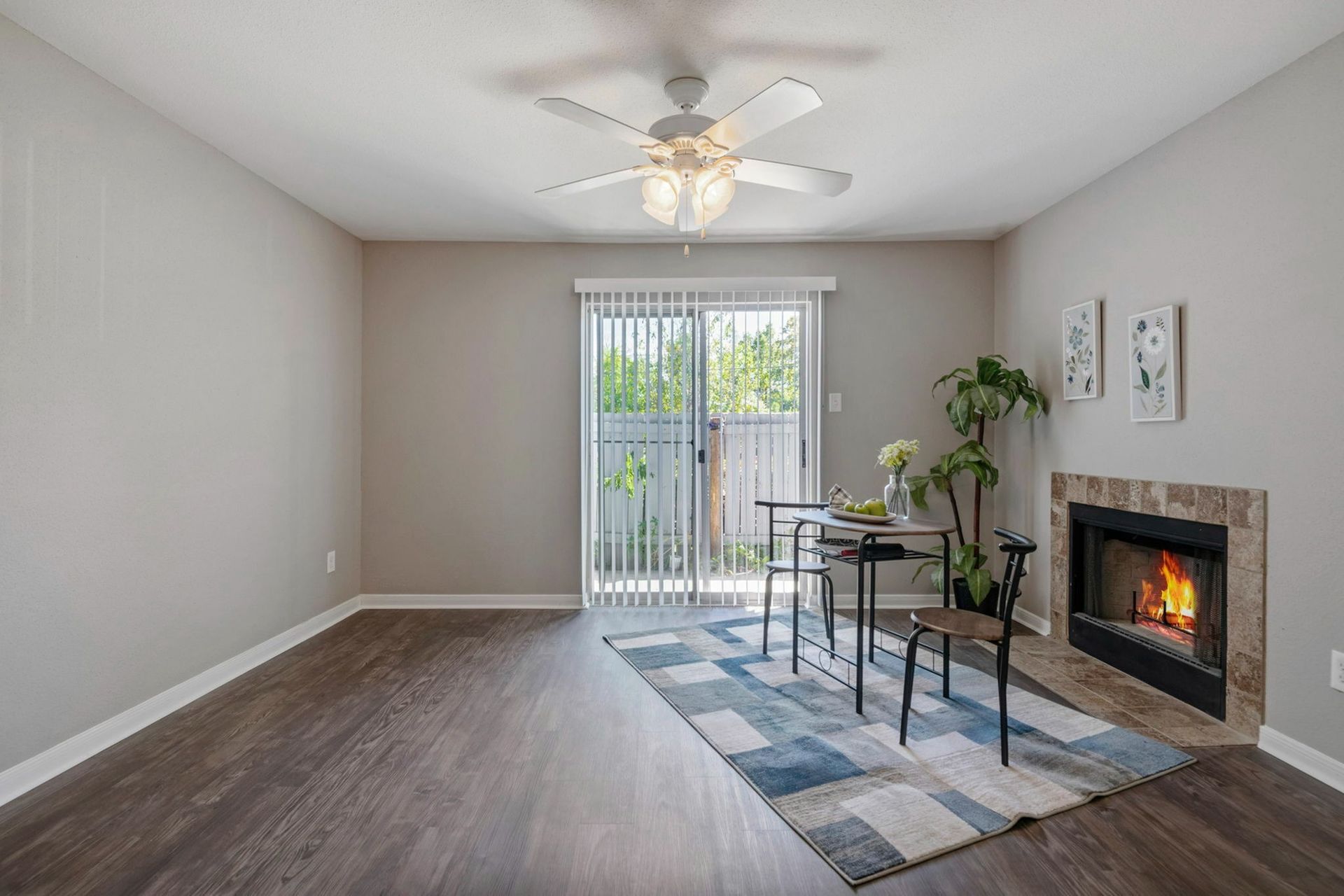 Living room in an apartment with a ceiling fan, gas fireplace, and sliding glass door.