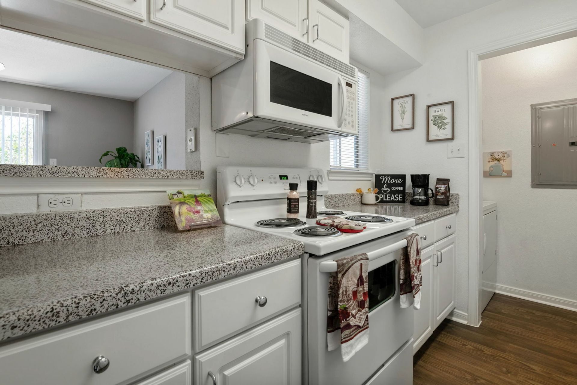 White kitchen with cabinets, granite countertops, stove, and over-the-range microwave in a compact layout.