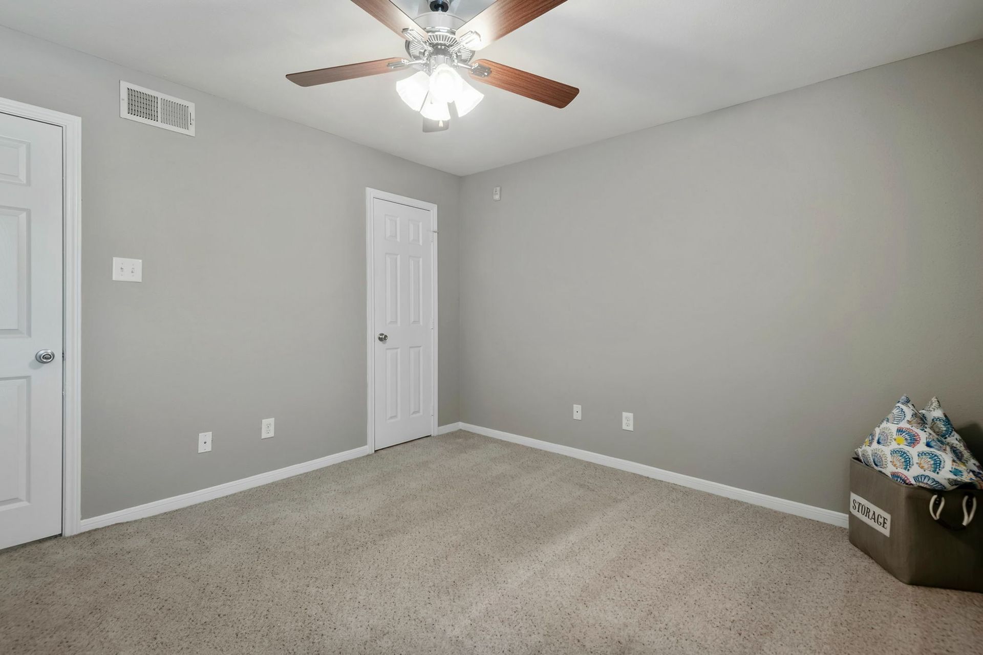 Empty bedroom with gray walls, beige carpet, and a ceiling fan.