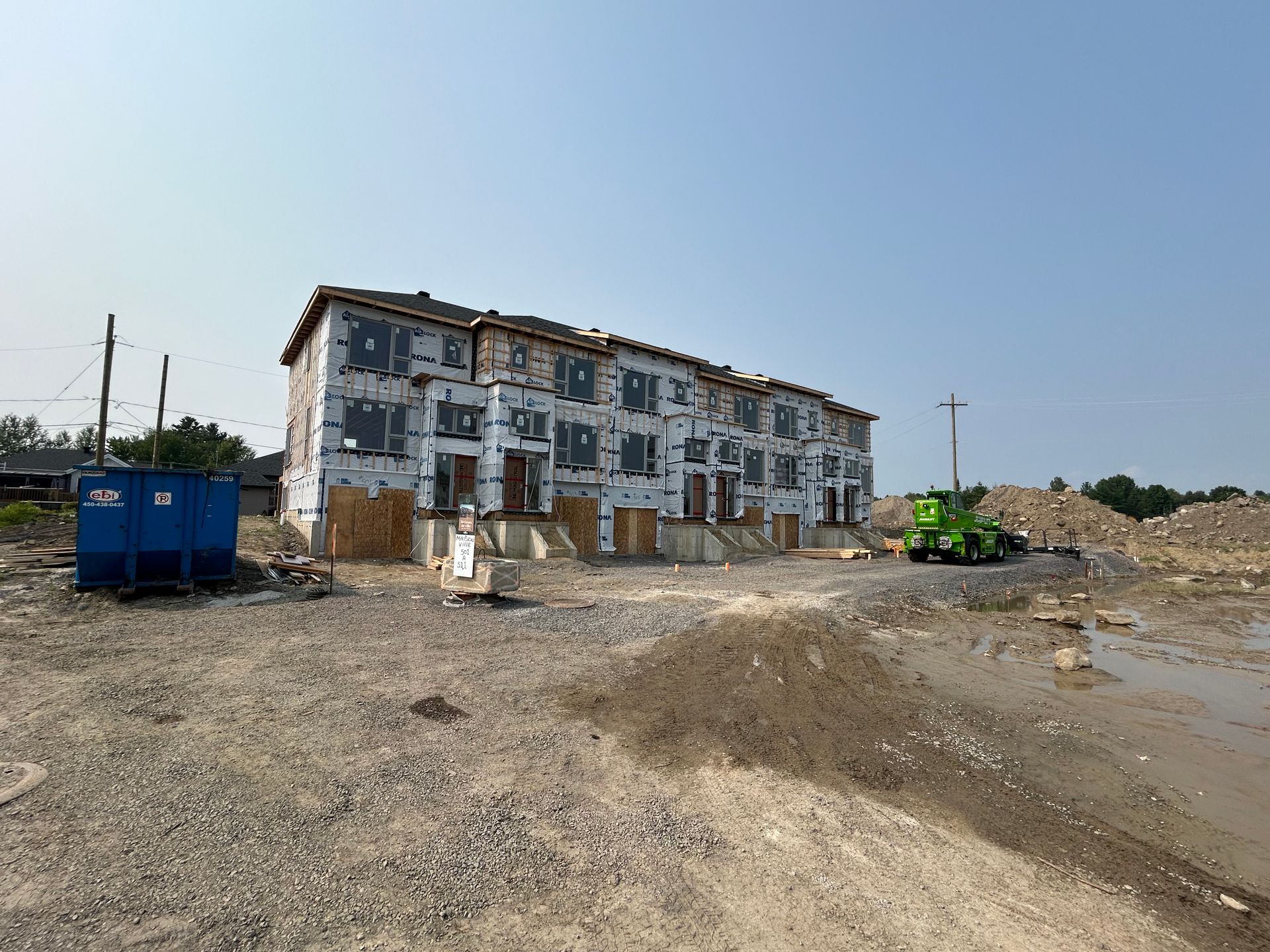 Maisons de ville à plusieurs étages en construction ; extérieur recouvert d'un matériau de protection ; chantier.