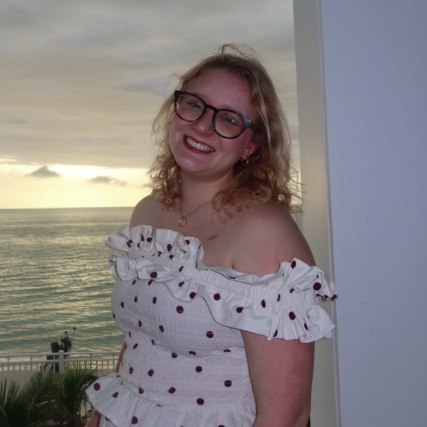A smiling person wearing glasses and a 