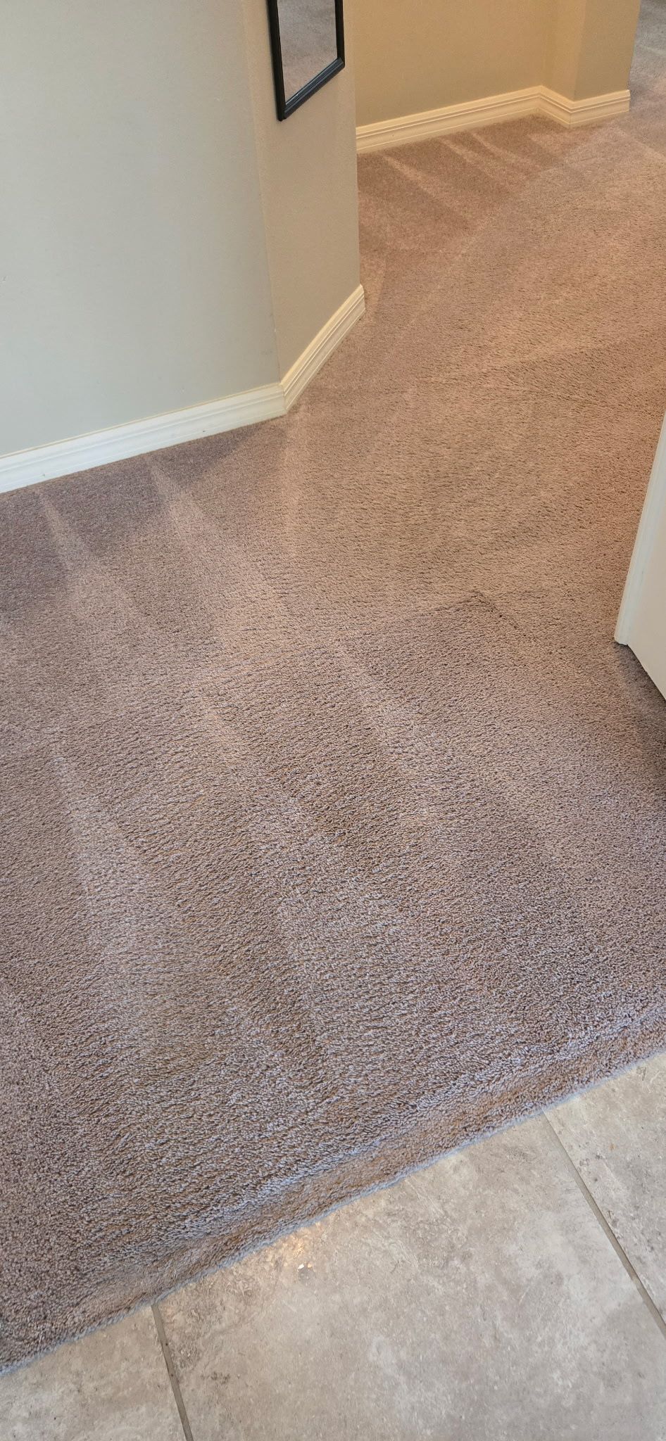 Carpeted hallway with beige walls and a tiled floor edge in the foreground