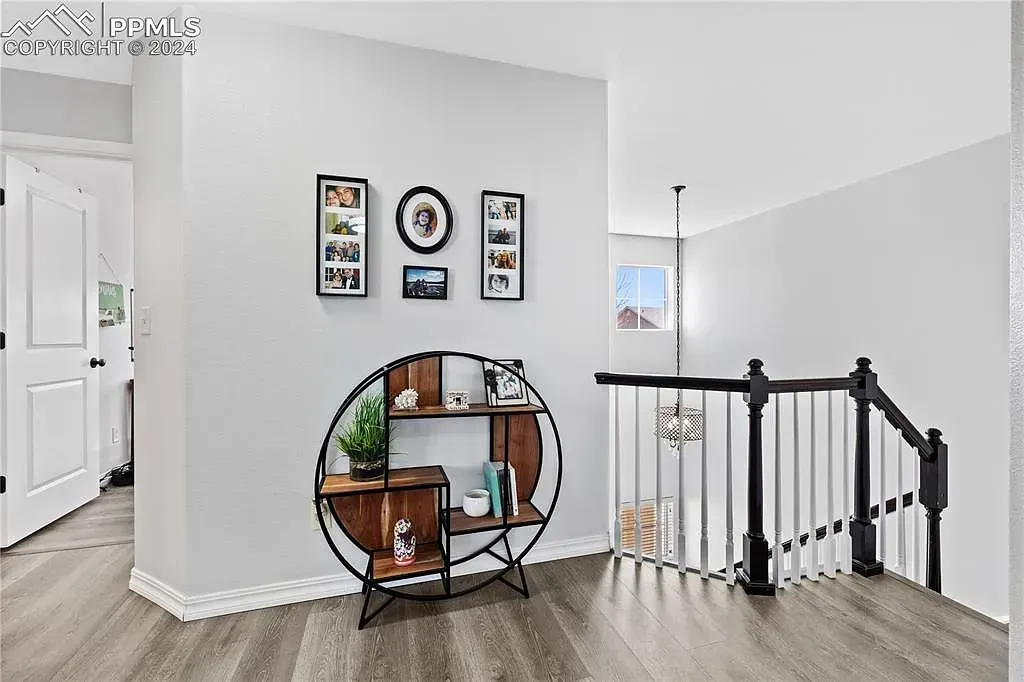 Bright hallway with wall art, round shelf, and staircase railing in a modern home