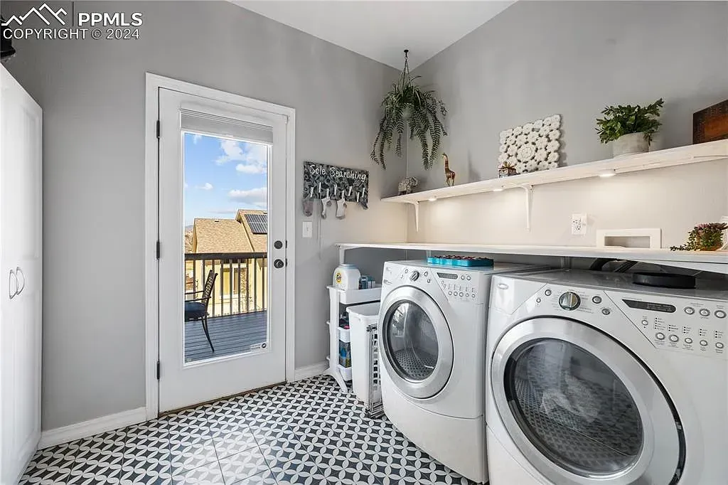Bright laundry room with washer and dryer, white shelves, gray walls, and patterned tile floor.