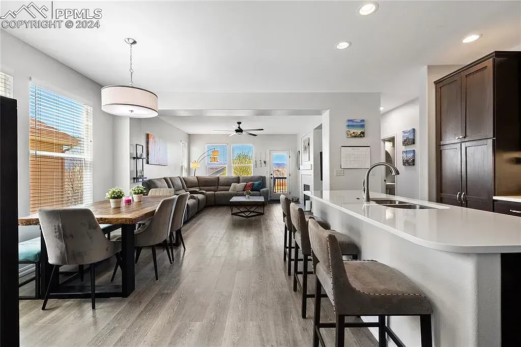 Bright modern open-plan kitchen and dining area with white island, bar stools, and dark dining chairs