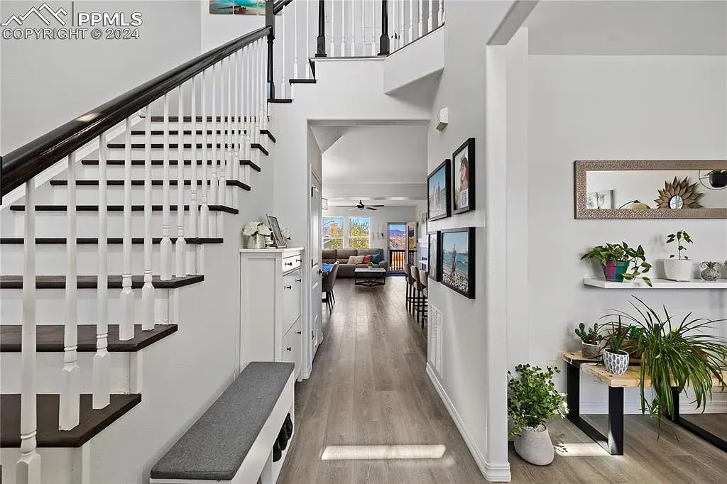 Bright modern hallway with a staircase, hardwood floor, and open living area beyond