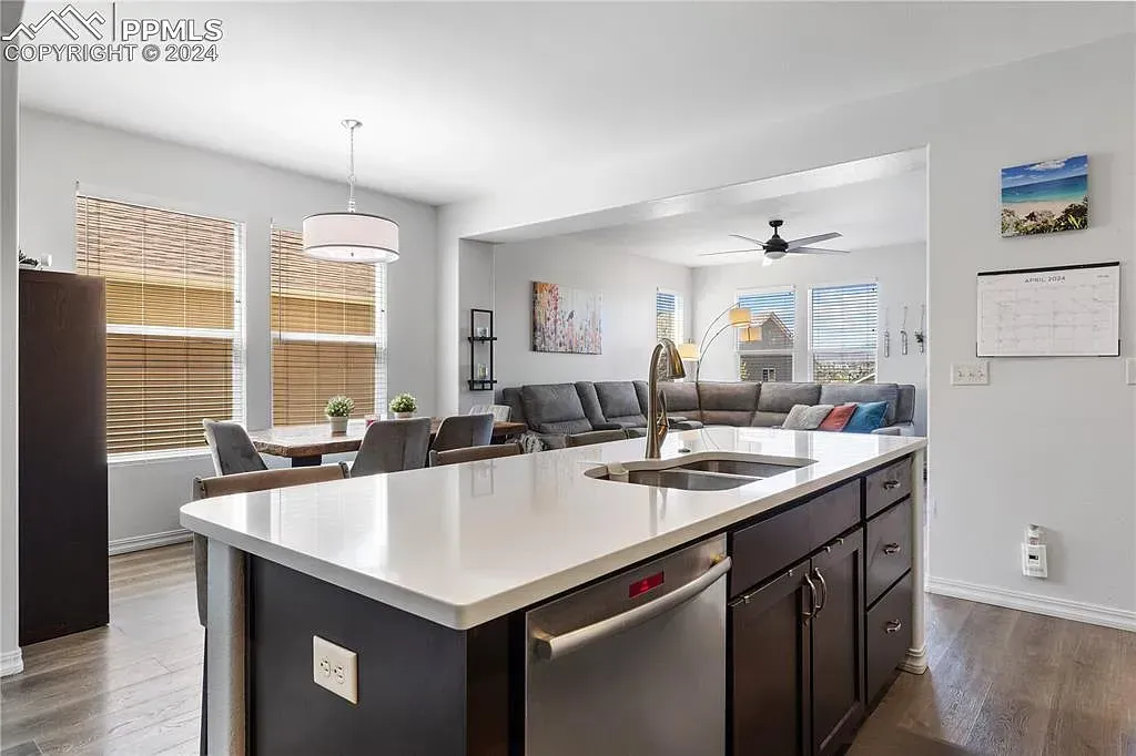 Modern kitchen with large island, dark cabinets, stainless appliances, and adjacent dining area