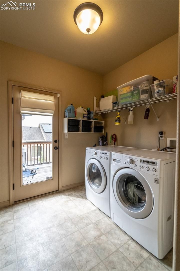 Laundry room with washer and dryer, shelves of supplies, and a door to the outside.