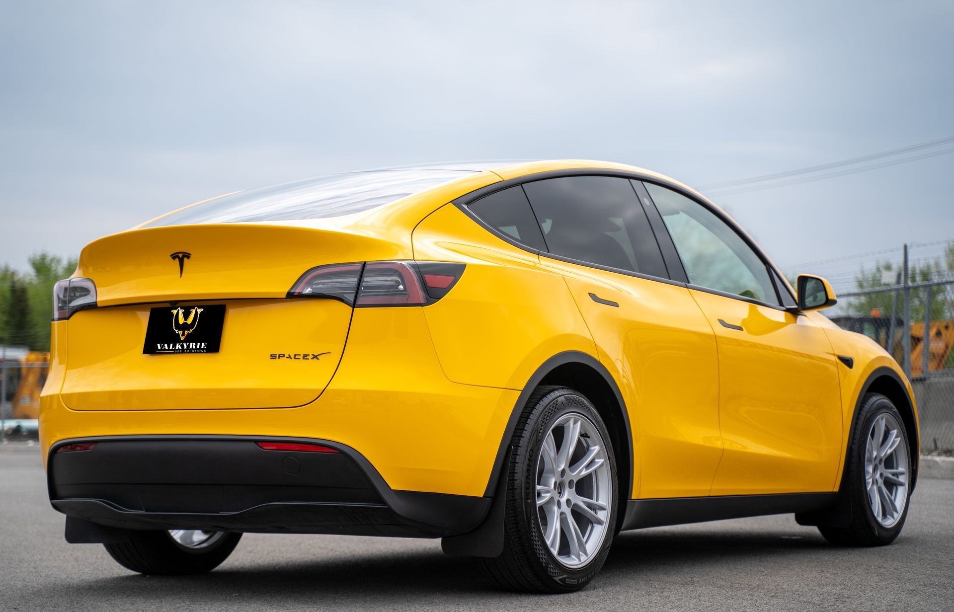 A yellow tesla model y is parked on the side of the road.