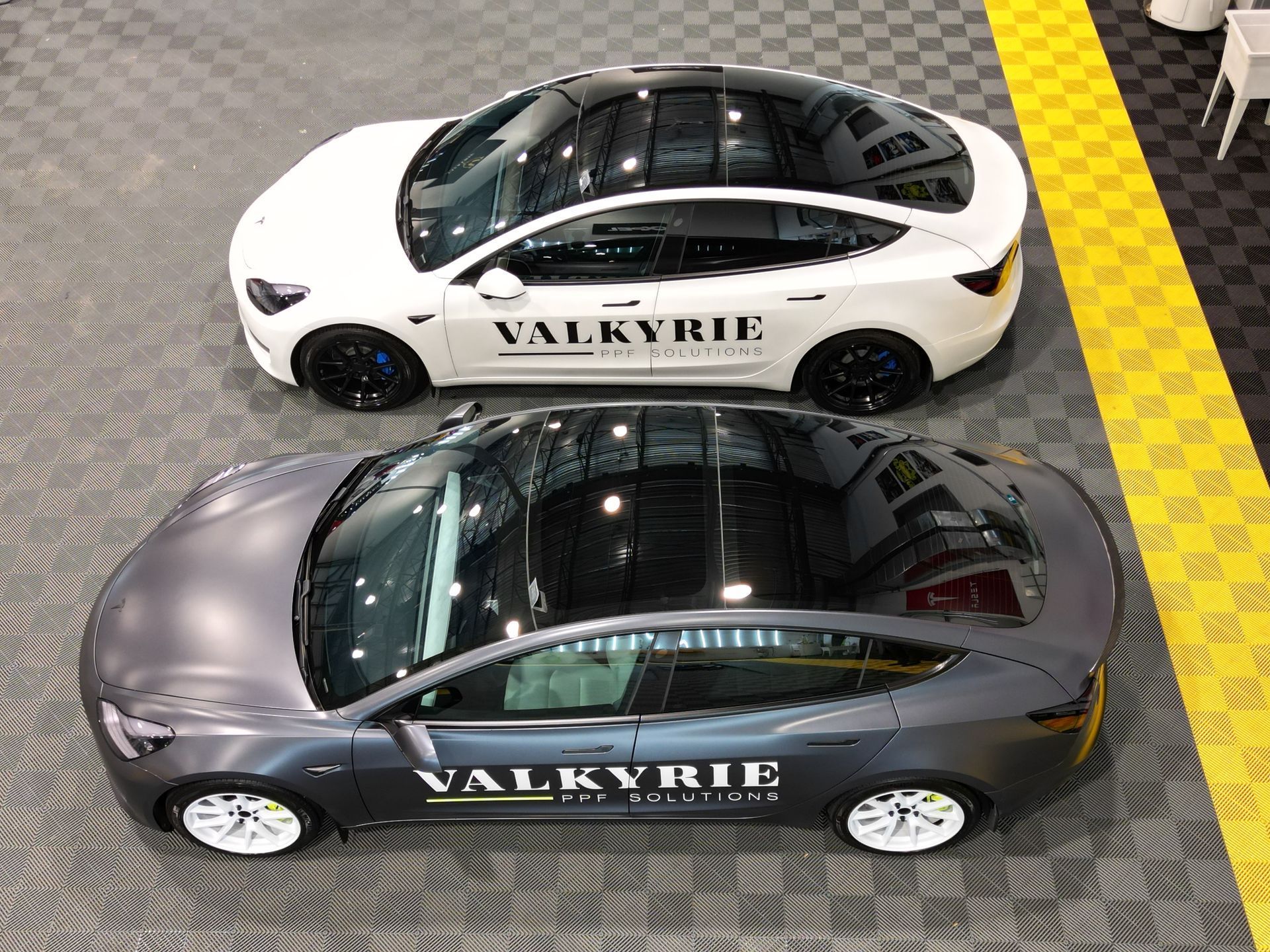 Two tesla model s cars are parked next to each other in a garage.
