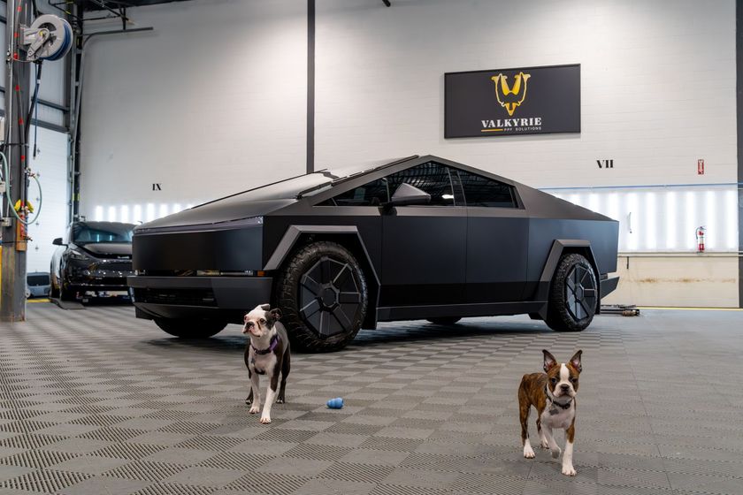 Two men are working on a car in a garage.