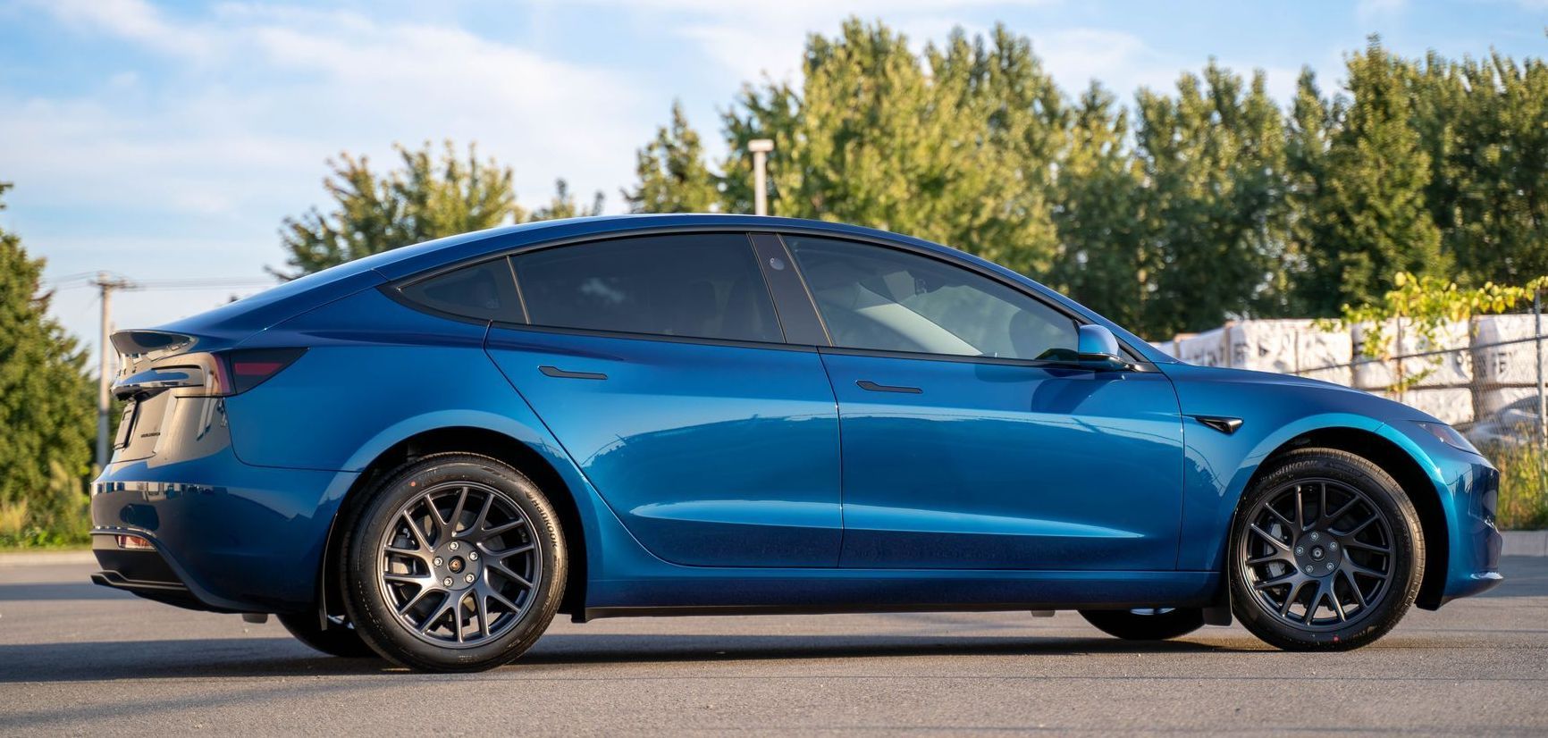 A yellow tesla model y is parked on the side of the road.