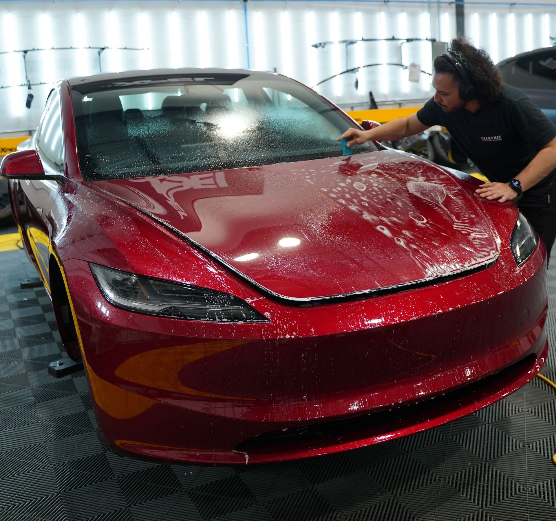 A man is cleaning the hood of a red car