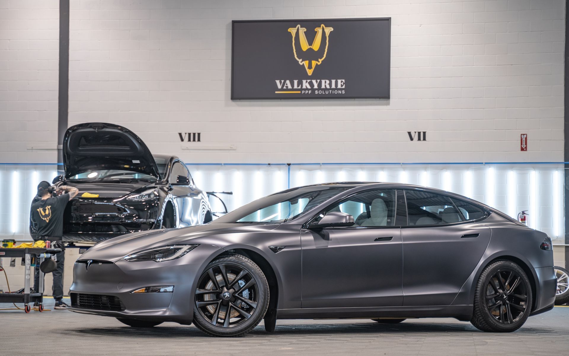 A red tesla model s is parked in a garage.