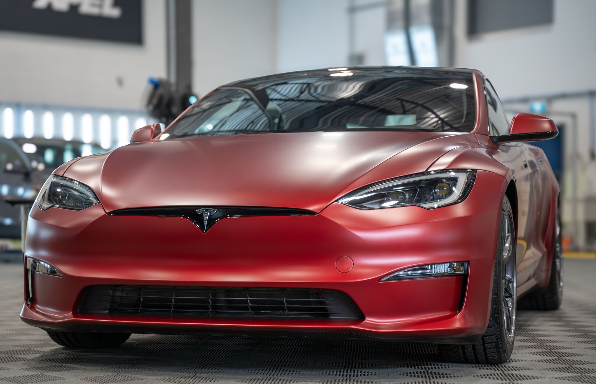 A red tesla model s is parked in a garage.