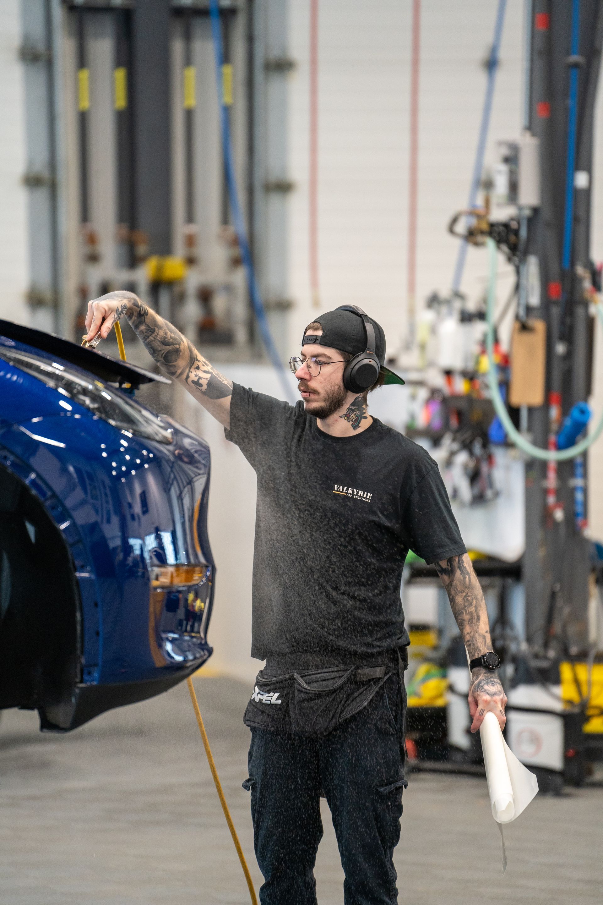 A man is washing a blue car in a garage.