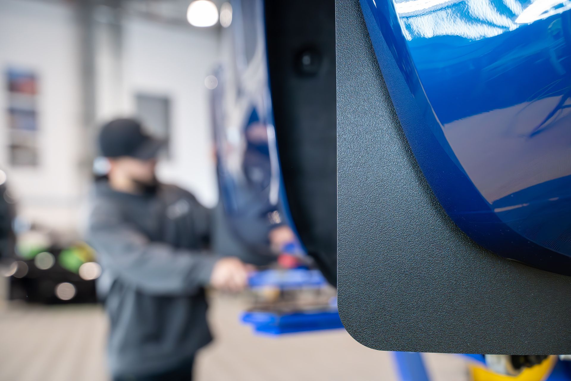 A blue tesla model 3 is parked in a garage.