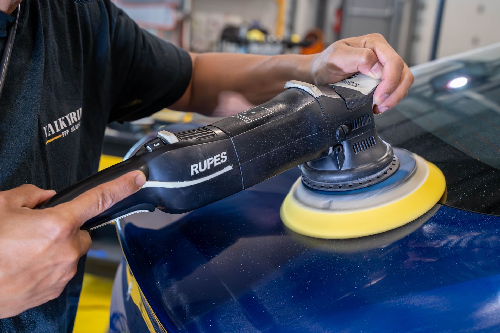 A man is polishing the windshield of a tesla model s in a garage.