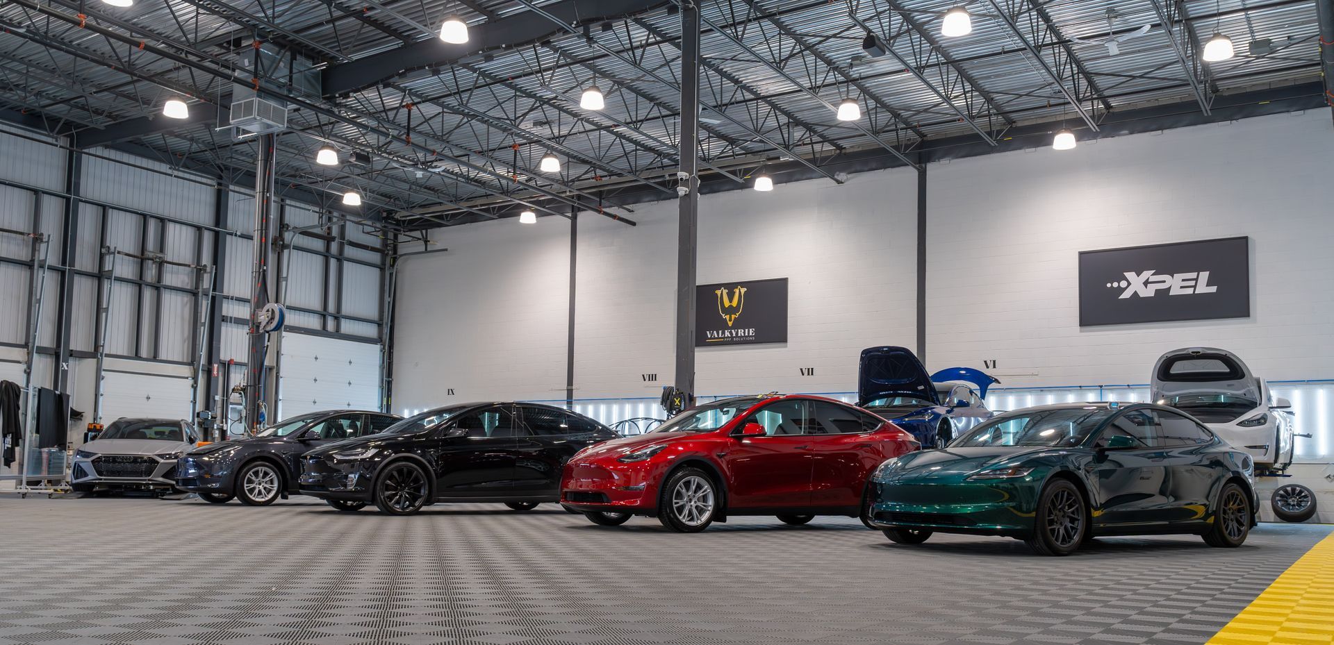 A tesla model 3 is sitting on a lift in a garage.