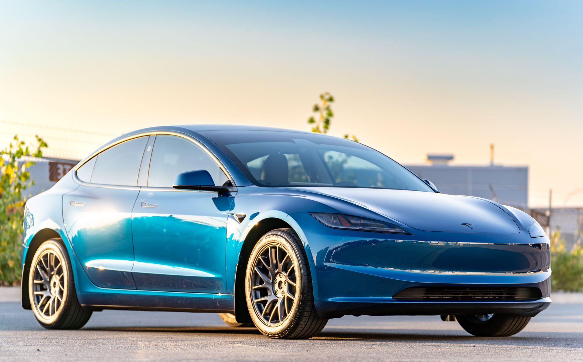 A green tesla model 3 is parked in a garage.