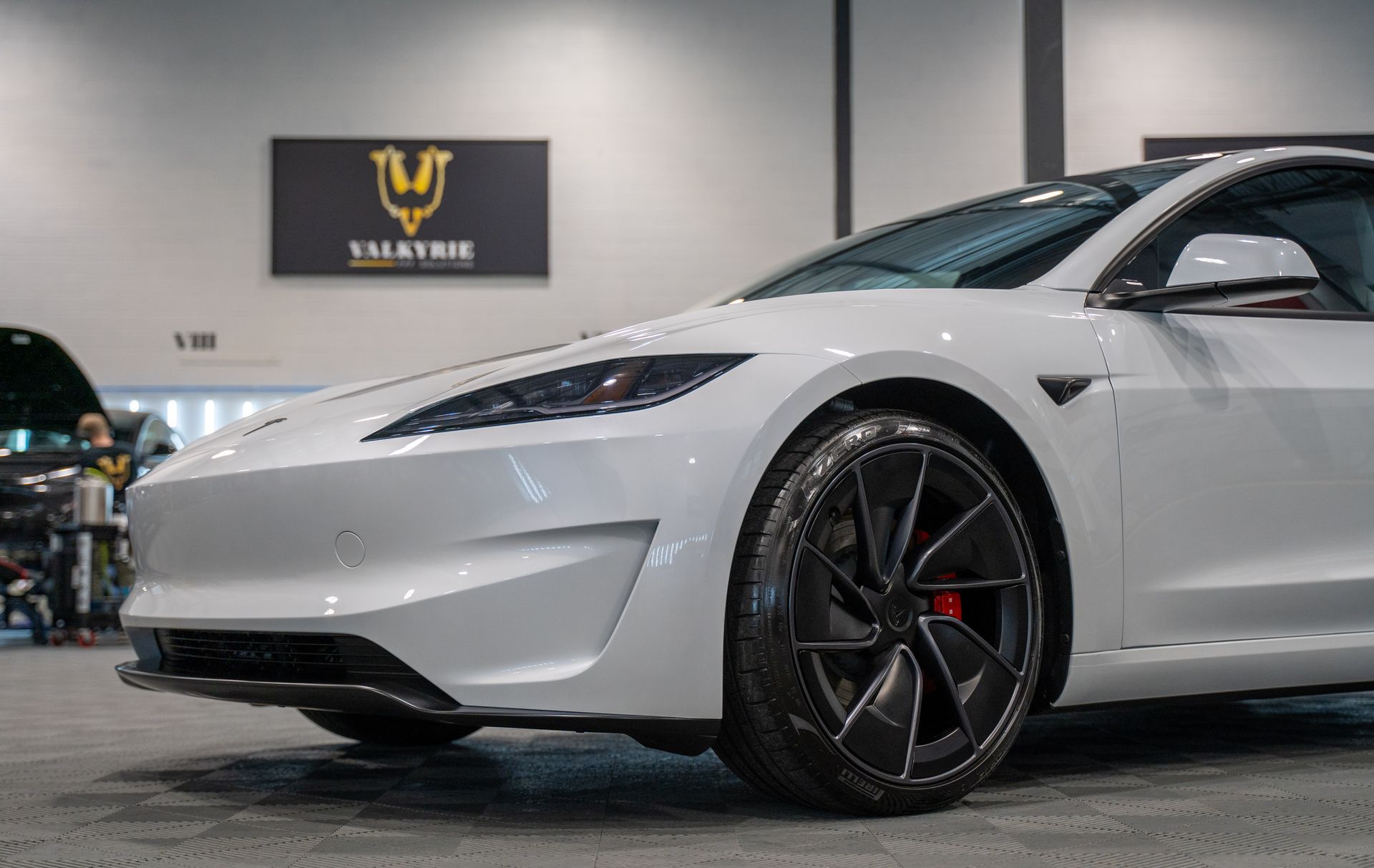 A blue tesla model 3 is parked in a garage.