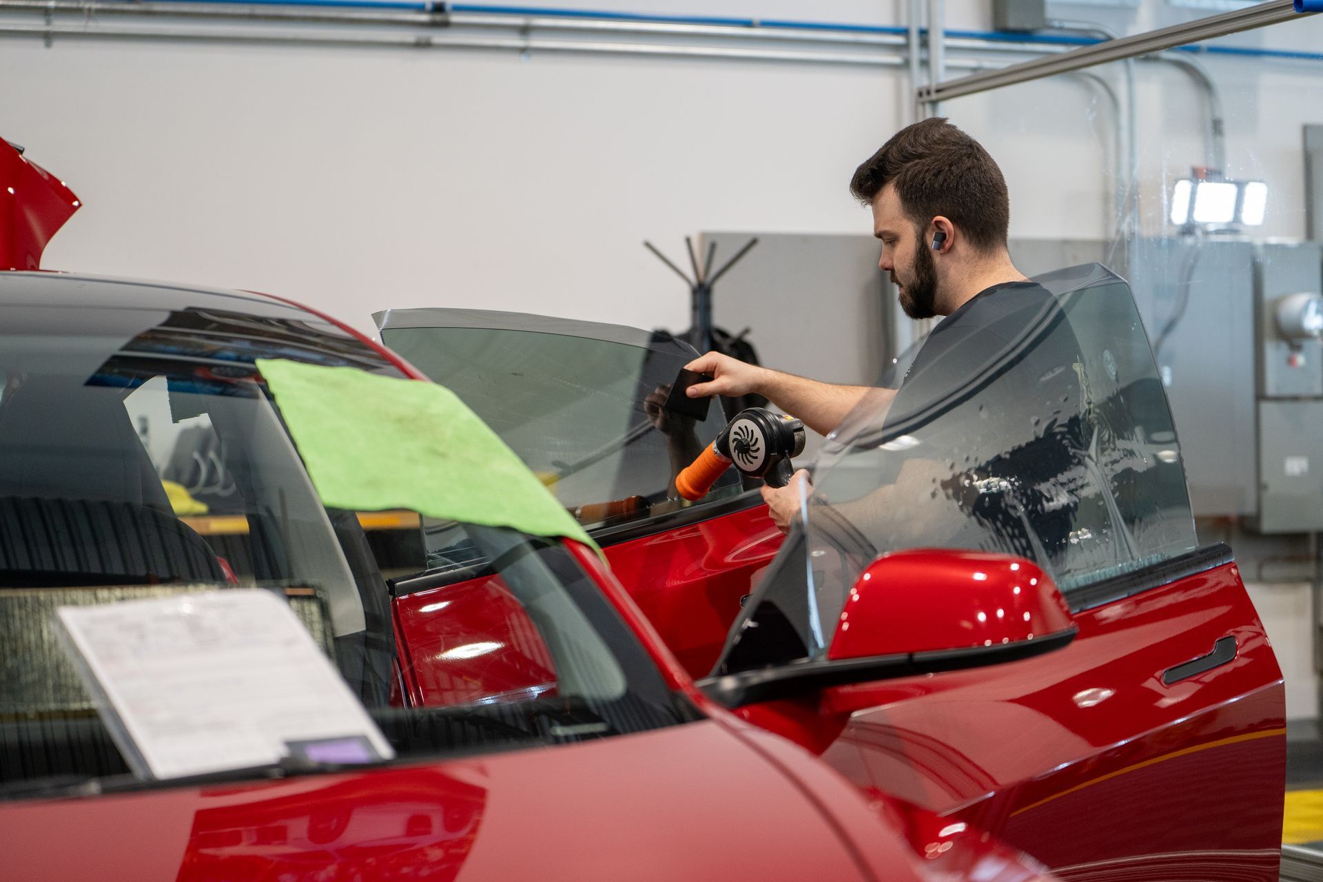 A man is working on a red car in a garage.