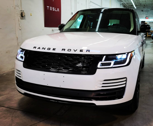 White Range Rover SUV parked indoors in a garage or showroom, front view