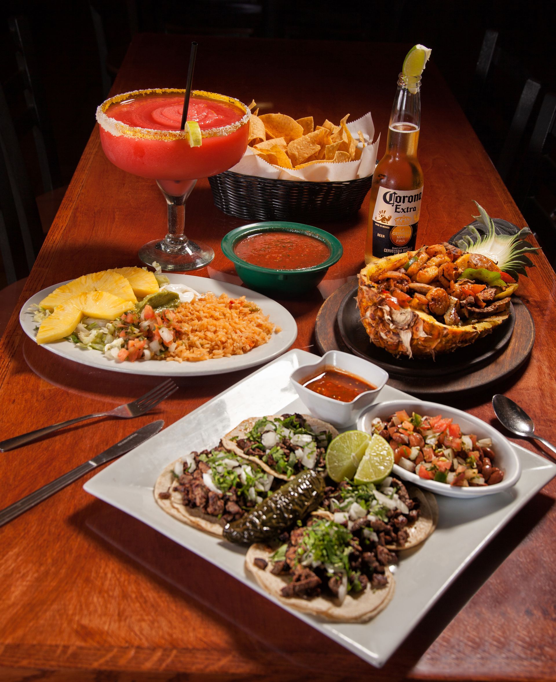 A table topped with plates of food and drinks including a bottle of corona