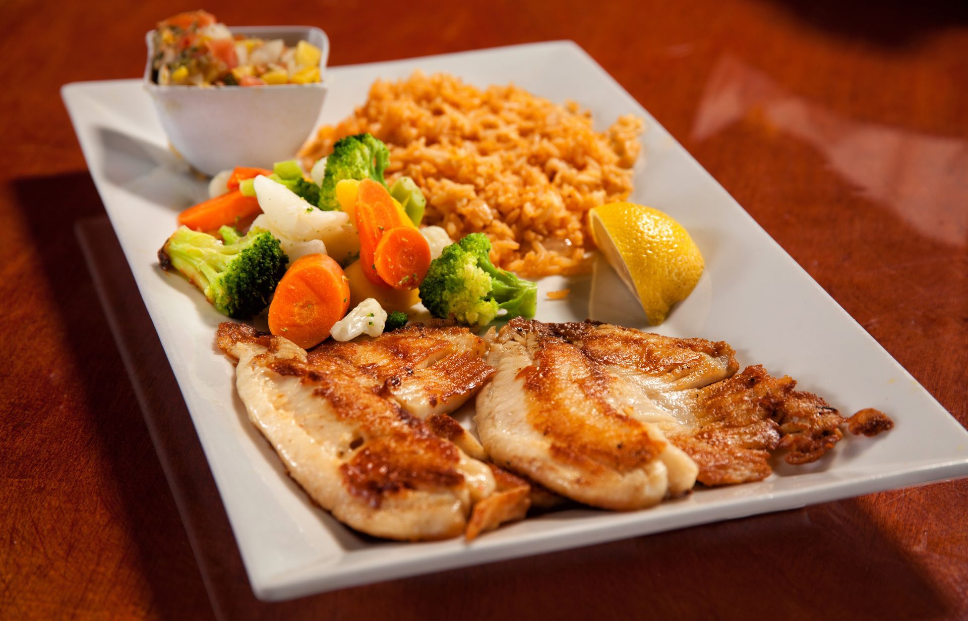 A white plate topped with chicken , rice and vegetables.