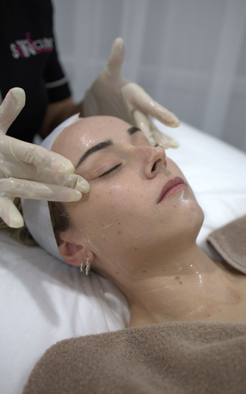 Facial spa treatment with a woman lying down as gloved hands massage her face. — Mackay Skin Clinic In North Mackay, QLD