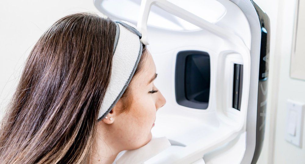 Woman undergoing a dental X-ray scan with her head positioned in the machine — Mackay Skin Clinic In North Mackay, QLD
