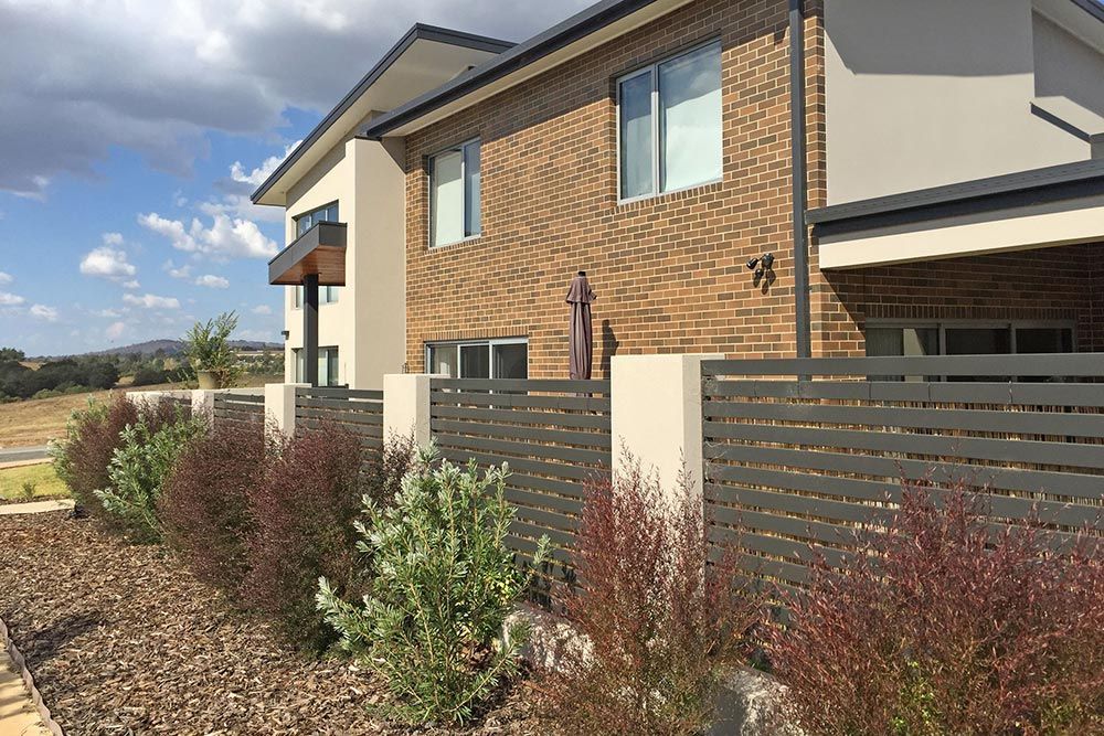 A Large Brick House With a Fence in Front of It — Imperial Build Co. in Coombs, ACT