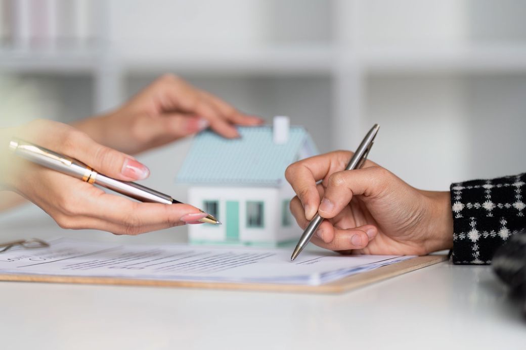 Una donna sta firmando un documento davanti a una casa modello.